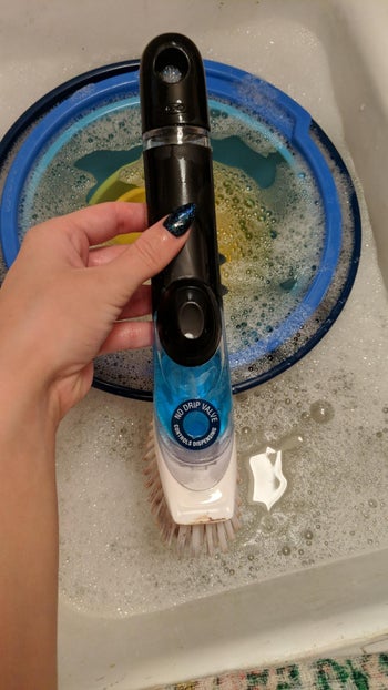 reviewer holding the soap dispensing brush
