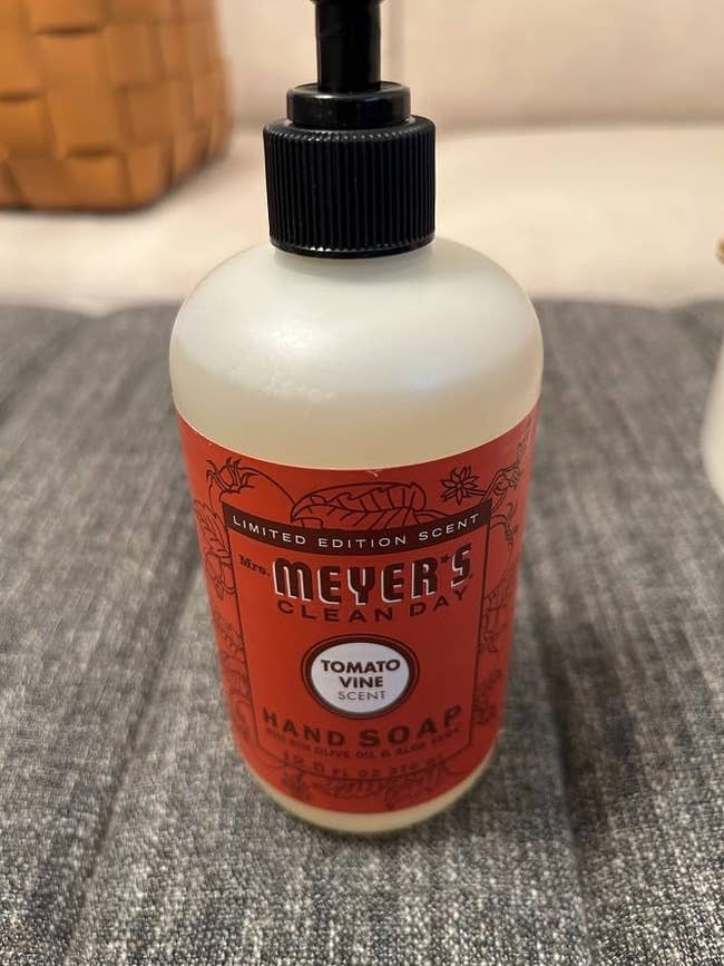 Mrs. Meyer's Clean Day manus  soap vessel  with herb  vine scent placed connected  a grey  surface