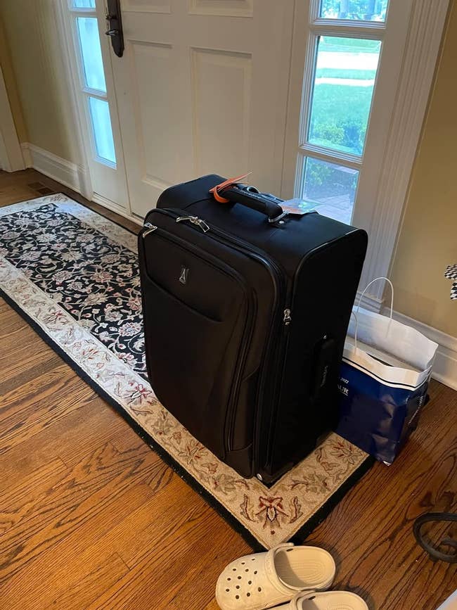 a reviewer's large black suitcase sitting by their front door