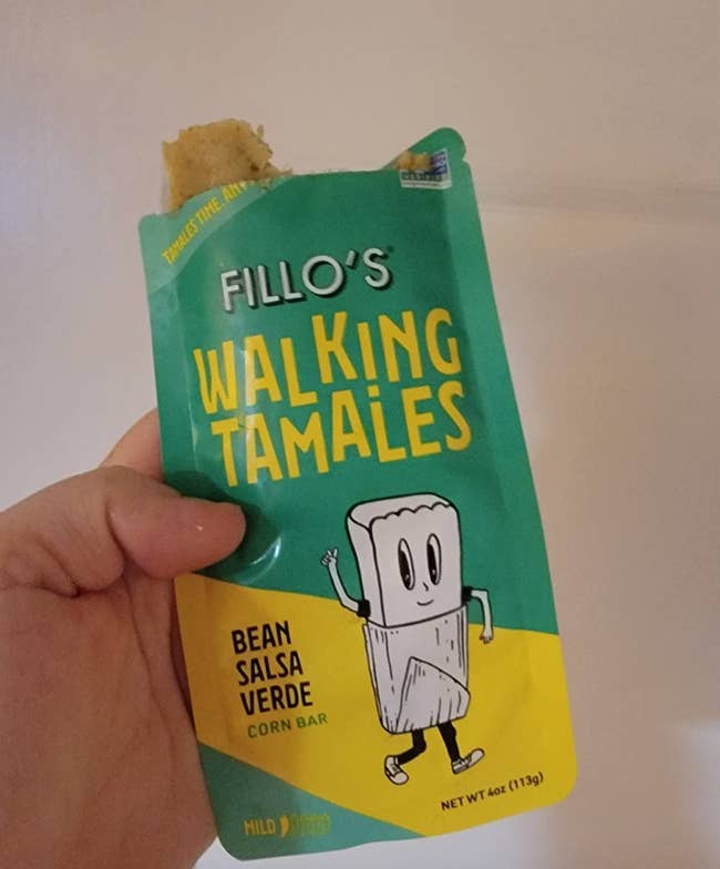 Reviewer holding a pouch full of a bean salsa verde tamale 