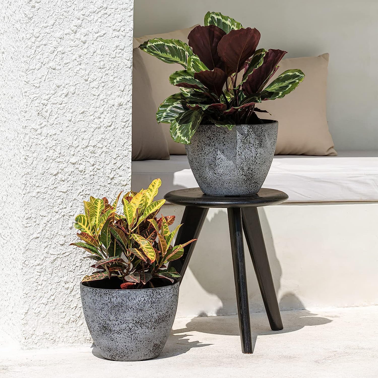 two stone look containers with flowers in them