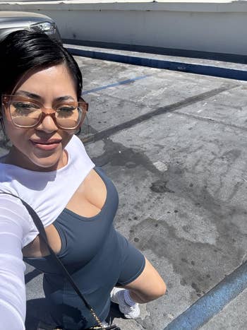 Person in stylish activewear poses outdoors, wearing glasses and sneakers