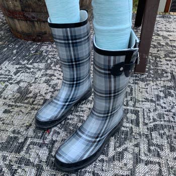 reviewer wearing plaid patterned rain boots