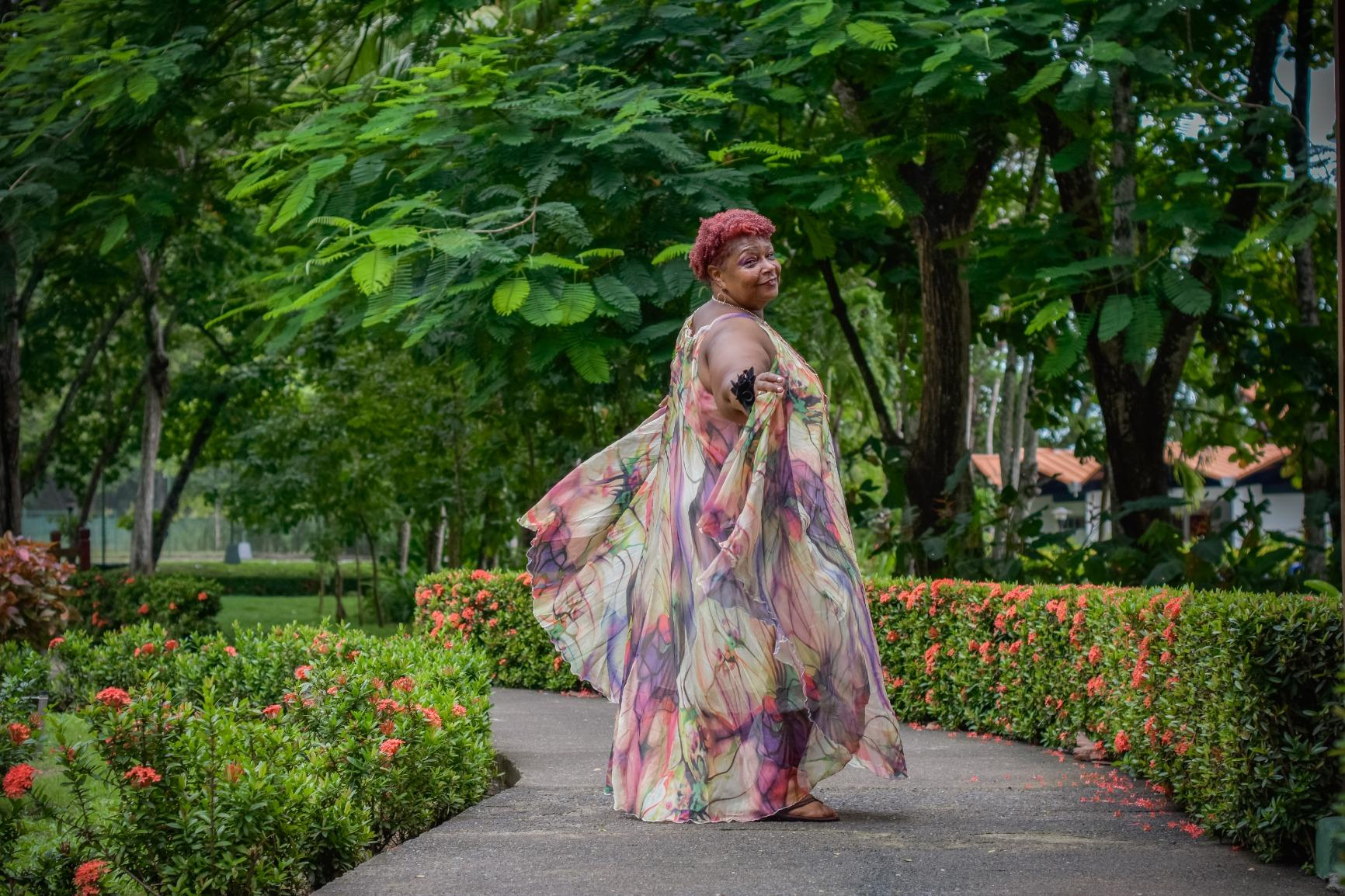 Reviewer in a flowy, floral dress posing on a garden path