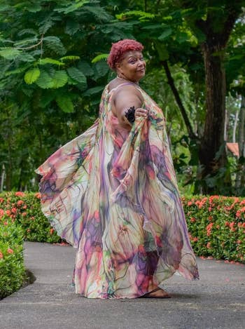 Reviewer in a flowy, floral dress posing on a garden path