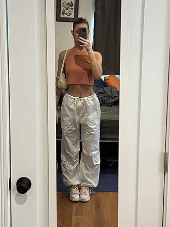 reviewer taking mirror picture in white baggy pants