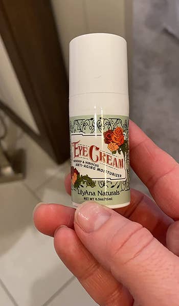 a reviewer holding the travel sized bottle of eye cream 