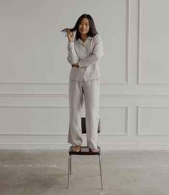 a model wearing linen pants and a long sleeve button up shirt in cream 