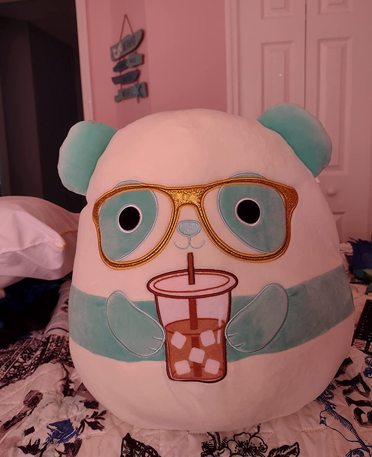 large oval shaped plush mint and white panda wearing gold glasses and holding iced coffee