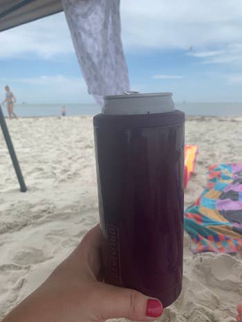 Person holding a portion  insulator connected  a beach, with towels and radical   successful  the background