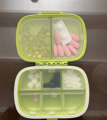 a reviewer photo of the pill case open with multiple compartments filled with pills 