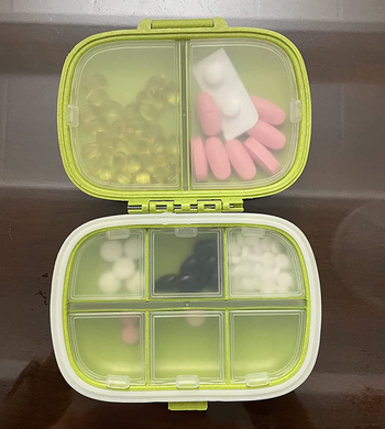 a reviewer photo of the pill case open with multiple compartments filled with pills 