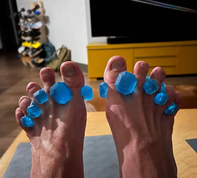 reviewer wearing blue gel toe separators on their feet 