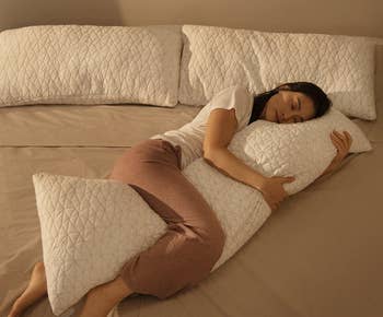 Image of a model laying down with the white pillow on a bed