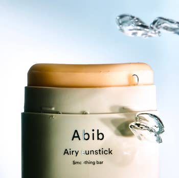 Close-up of an Abib Airy Sunstick with h2o  splashes, highlighting its creaseless  texture for imaginable   shoppers