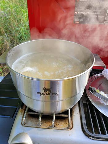 reviewer photo using stainless steel pot boiling over camp grill