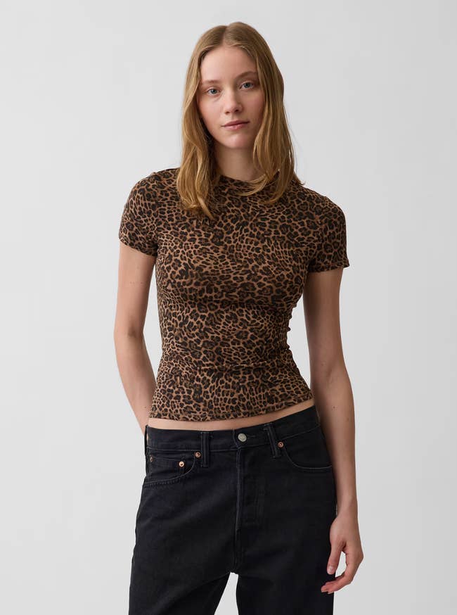 Person wearing a fitted leopard people     garment  and acheronian  jeans, posing successful  a neutral setting