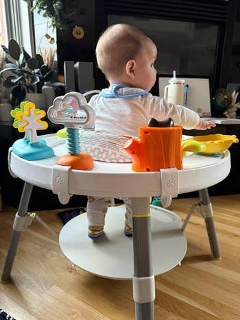 Baby seated successful an enactment halfway with assorted interactive toys, looking away