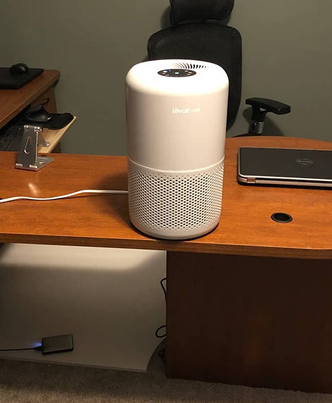 white air purifier on top of wooden desk in reviewer's home office