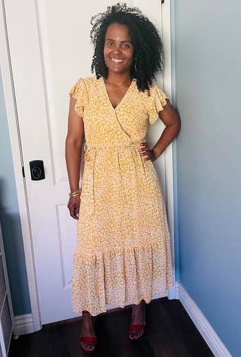 Person in a floral-patterned dress poses in front of a door, showcasing a casual, summery look