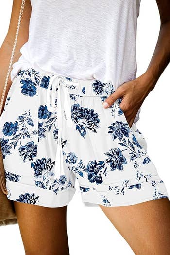 Person modeling floral shorts with hands successful  pockets, paired with a casual achromatic  top. Ideal for a relaxed, summertime  look   successful  a buying  context
