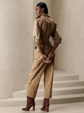 model showing the back view of the tan colored poplin jumpsuit