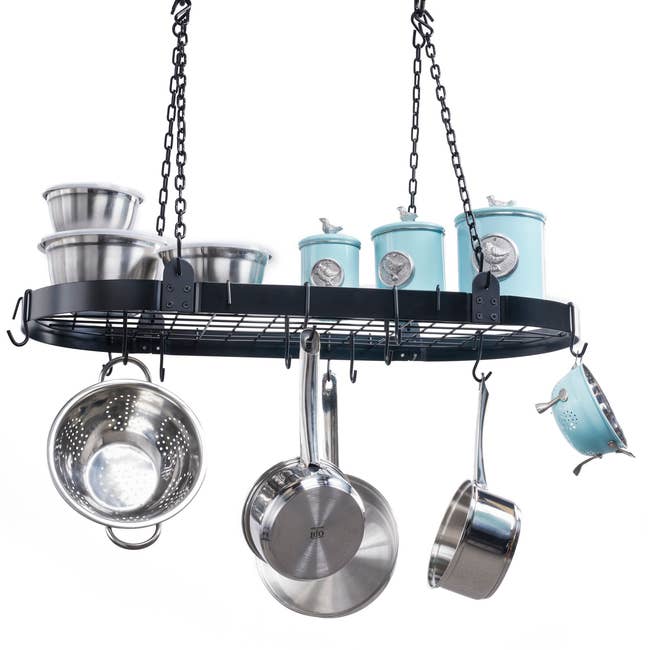 A black pot hanger with silver and blue pots hanging from it