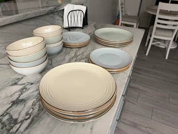 Stacks of ceramic plates and bowls successful neutral tones connected a marble countertop, suggesting a stylish and elegant tableware enactment for location dining