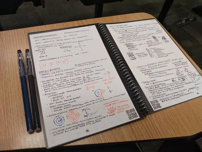 Notebook unfastened  connected  a table  with handwritten chemistry notes and diagrams, 2  pens placed beside it