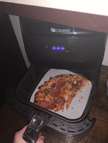 reviewer using air fryer to heat up pizza