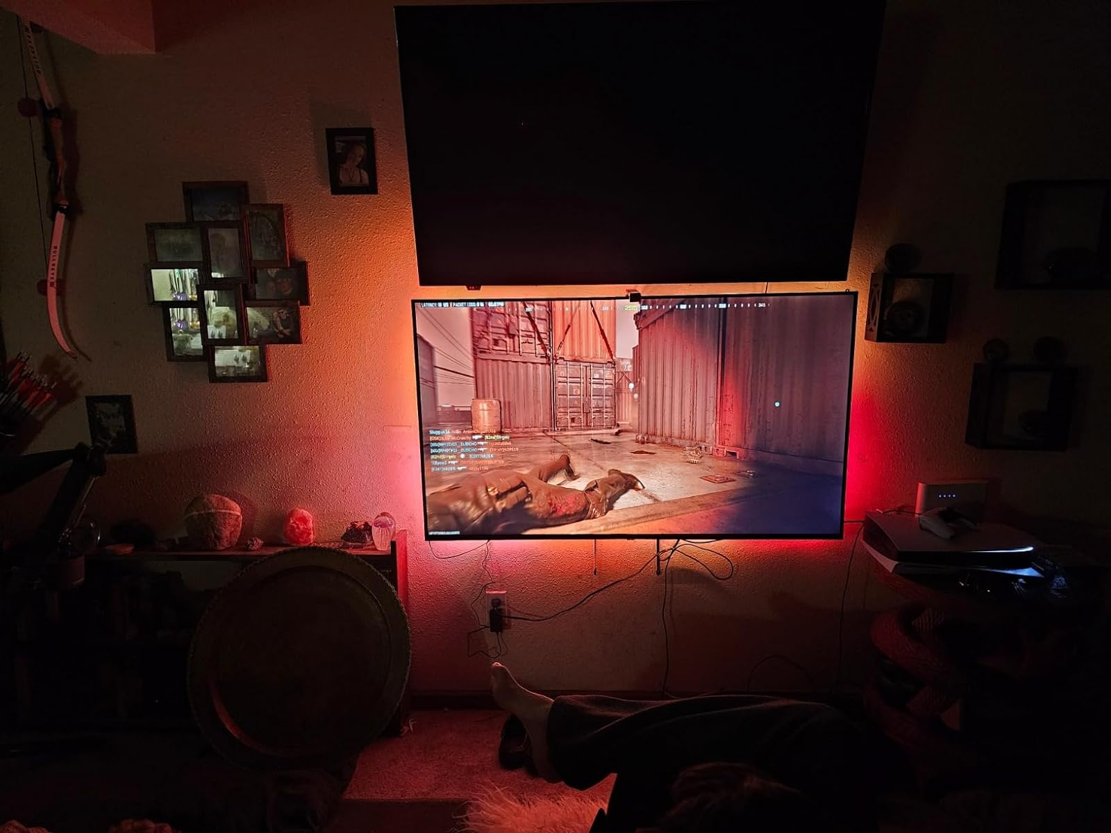 Gaming setup with a large screen displaying a game, ambient lighting, and a comfy seating area