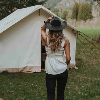 Person in casual attire with a hat facing a canvas tent, image related to outdoor apparel shopping