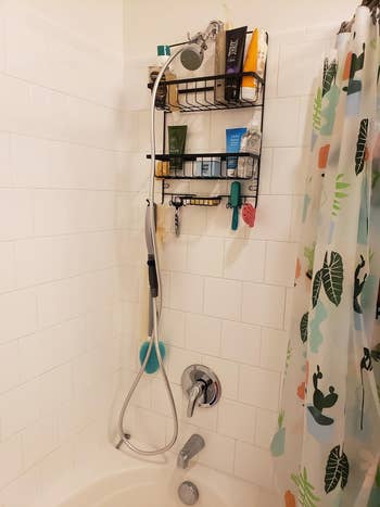 Reviewer's shower with hanging grooming tool attached to suction cup on wall