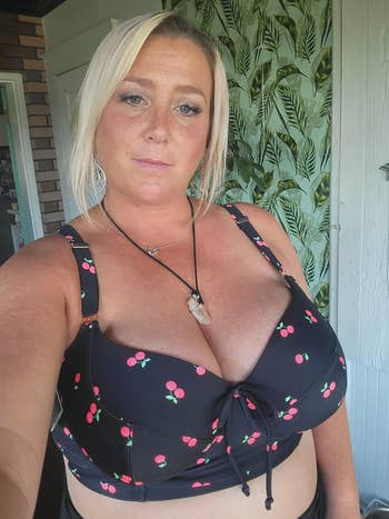 a reviewer wearing the swim top in black featuring a cherry print 