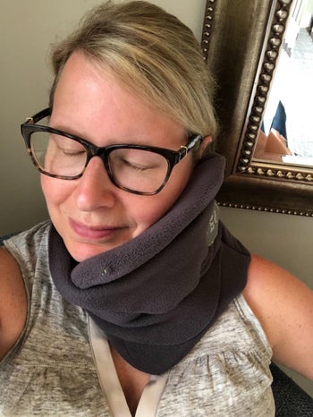 another reviewer wearing the same neck pillow in a gray color