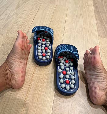 Person trying on acupressure slippers, feet beside them on floor