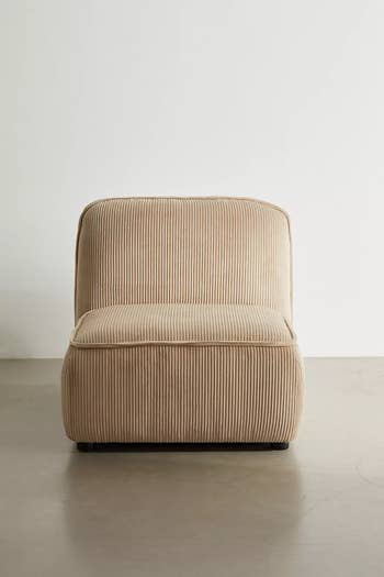 Beige ribbed accent chair with a minimalist design on a neutral background. Suitable for modern home decor