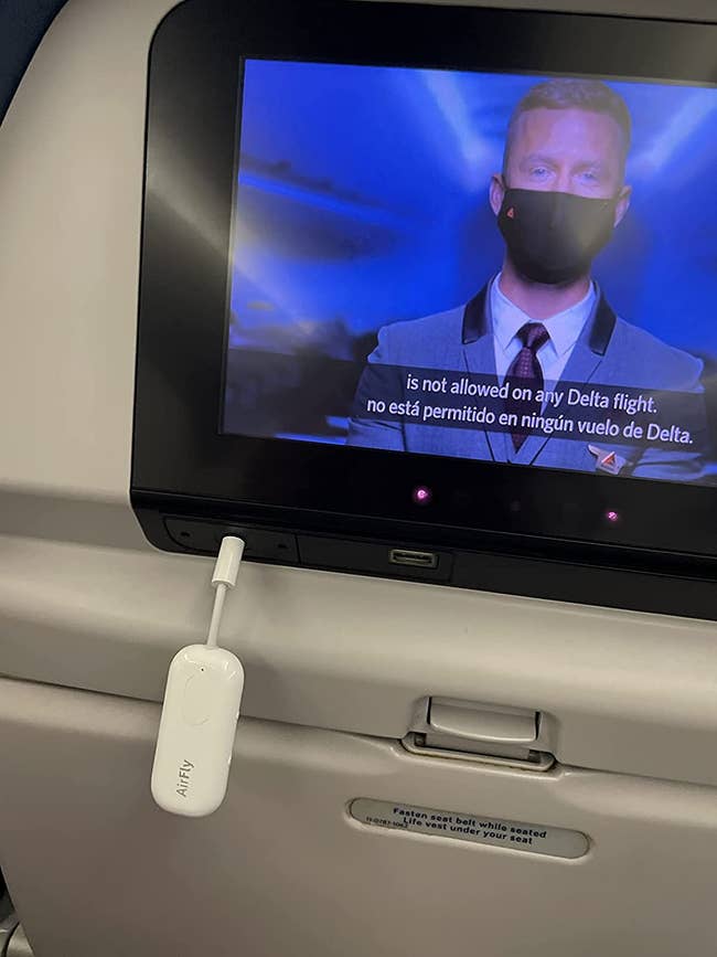 reviewer photo of the airfly device plugged into the headphone jack of an airplane screen