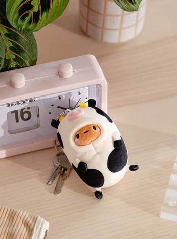 the keychain with a little potato face peeking out of a cow suit