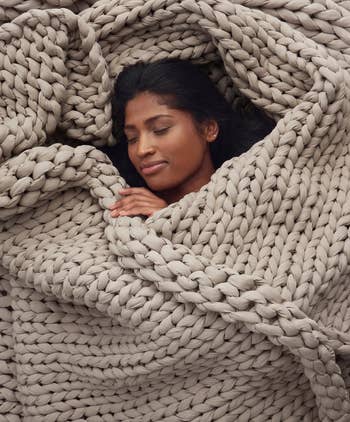 Person resting comfortably wrapped successful a large, chunky knit blanket