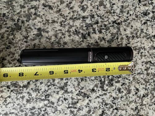 A sleek black collapsible selfie stick next to a measuring tape showing it is approximately 6 inches long