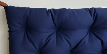 Navy blue tufted cushion attached to a white wall