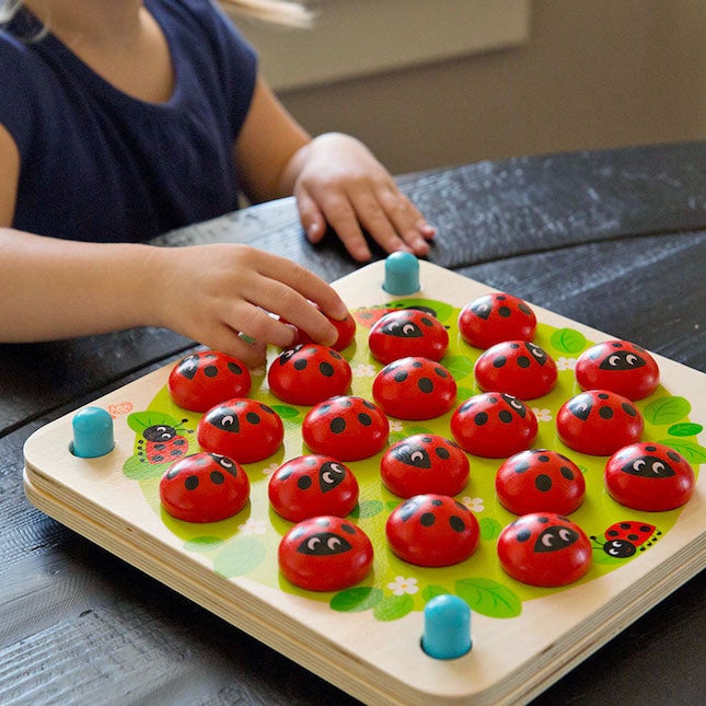 Model playing with wooden ladybug garden memory game