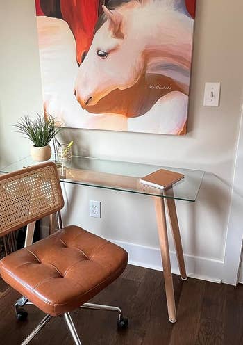 a reviewer's home office with a painting of two horses, a wooden desk, and a leather chair