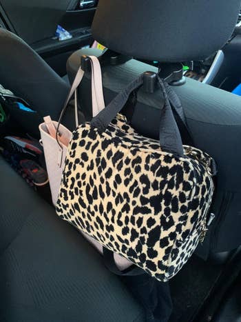 black hooks with a pink tote and leopard-print tote behind car seat 