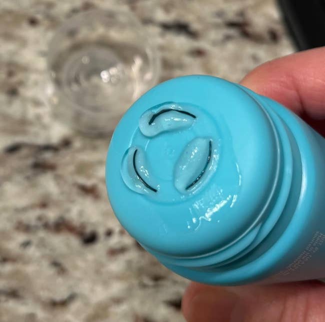 Close-up of a manus  squeezing a bluish  skincare conduit  with wide   gel emerging. The inheritance  shows a granite countertop