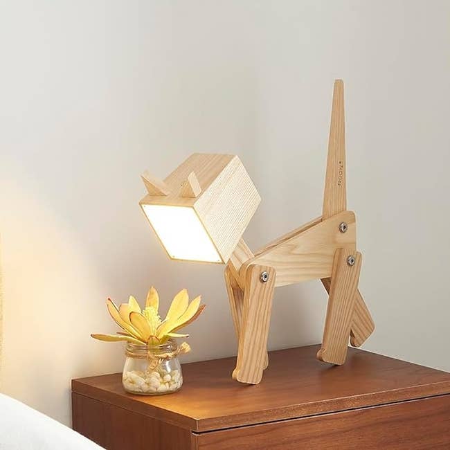 abstract cat shaped lamp with four legs, a tail, and a square head with a light surface 