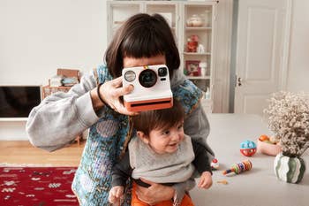 Person playfully holding a camera to their oculus  portion    holding a smiling kid  successful  a cozy, location  setting