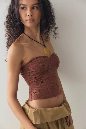 Person wearing a strapless lace top and a statement necklace, looking sideways. Relaxed hairstyle. Fashion-focus for shopping context