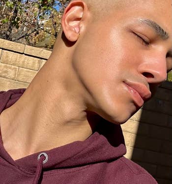 Person outdoors with closed eyes wearing a casual hoodie. Peaceful look suggests relaxation